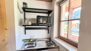 Une cuisine compacte équipée d’un four à micro-ondes encastré, d’un évier et d’une fenêtre donnant sur l’extérieur.