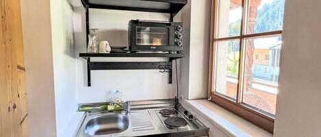 A compact kitchen with a built-in microwave, a sink, and a window providing a view of the outside.