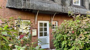 A brick house with a white door and a small porch area. - Gaathüs - Stylish vacation home under thatch in Keitum (Sylt-Ost)