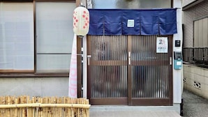 A traditional Japanese entrance with a sliding door, a security camera, and a CCTV sign.
