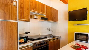 Una cocina compacta con armarios de madera, horno empotrado, microondas y un lavamanos pequeño.