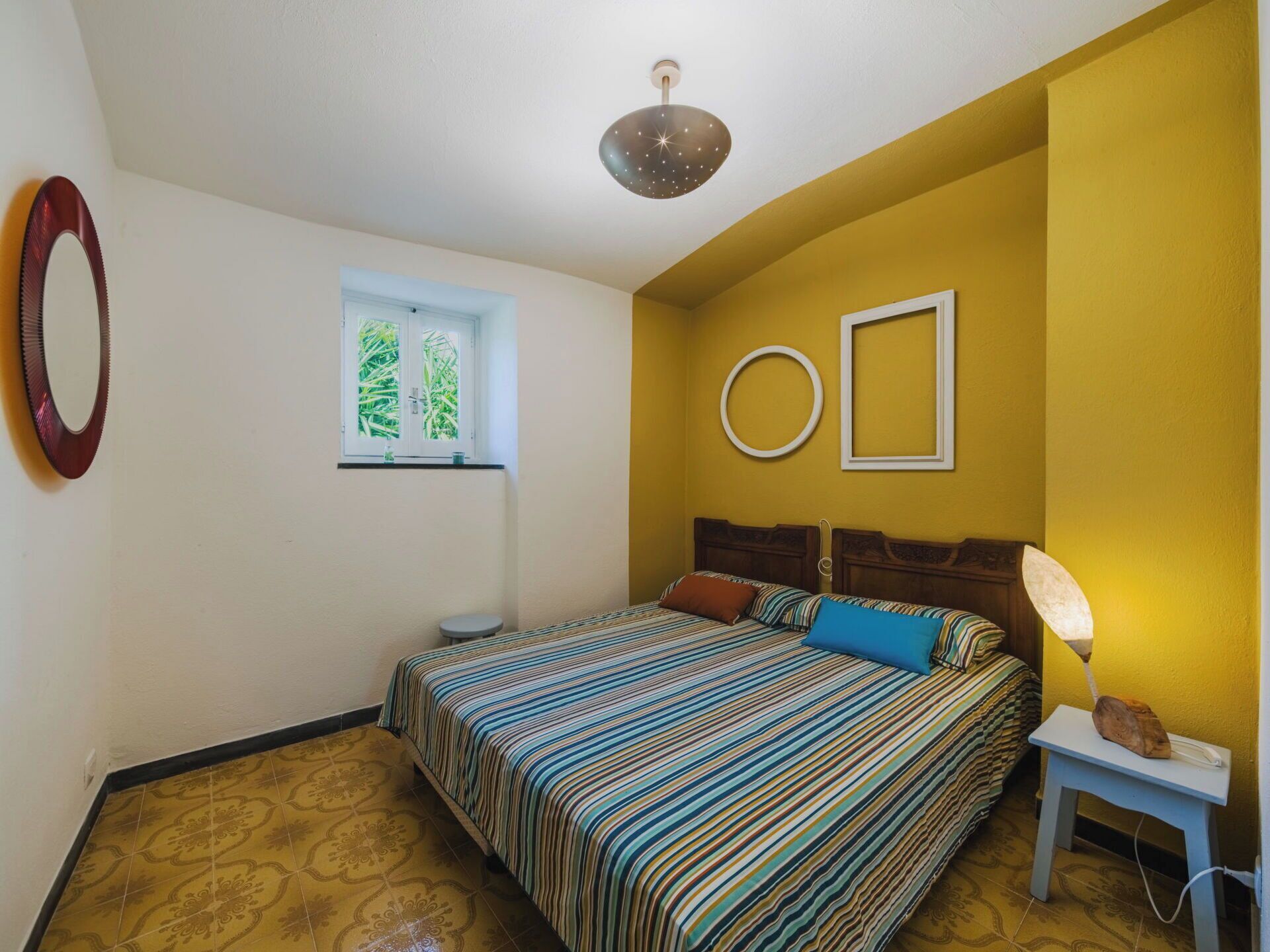Quarto com cama, janela, espelho e luminária no teto.