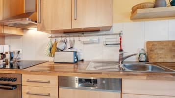 Een moderne keuken met houten kastjes, een roestvrijstalen vaatwasser en een ingebouwde oven.