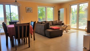 A living room with a sofa, a dining table, and a TV. - Holiday Apartment Bär, 59 sqm, 1 Bedroom, Living and Dining Area, max. 3 Persons (Rosengarten)