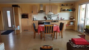 Une cuisine compacte avec des meubles en bois, une table à manger avec des chaises, un four encastré et une grande fenêtre.