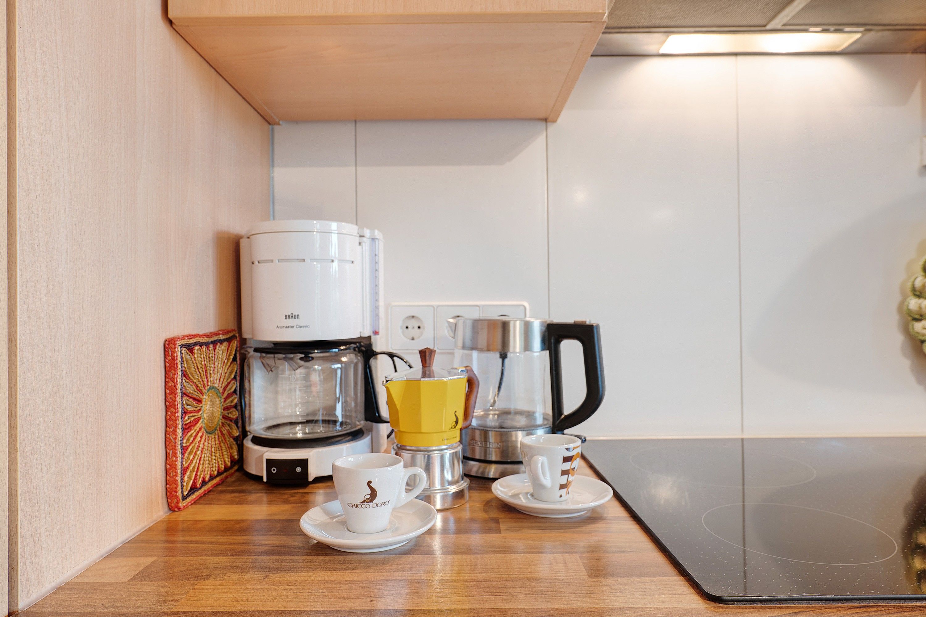 Et tekøkken med kaffemaskine, elkedel og to kopper på disken.
