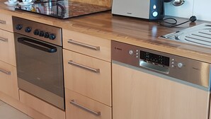 A kitchen with a stainless steel oven, a Bosch dishwasher, wooden cabinets, and a countertop with a toaster. - Holiday Apartment Bär, 59 sqm, 1 Bedroom, Living and Dining Area, max. 3 Persons (Rosengarten)