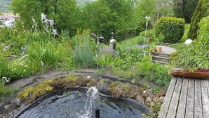 A garden with a pond, various plants, and a wooden deck. - Holiday Apartment Bär, 59 sqm, 1 Bedroom, Living and Dining Area, max. 3 Persons (Rosengarten)