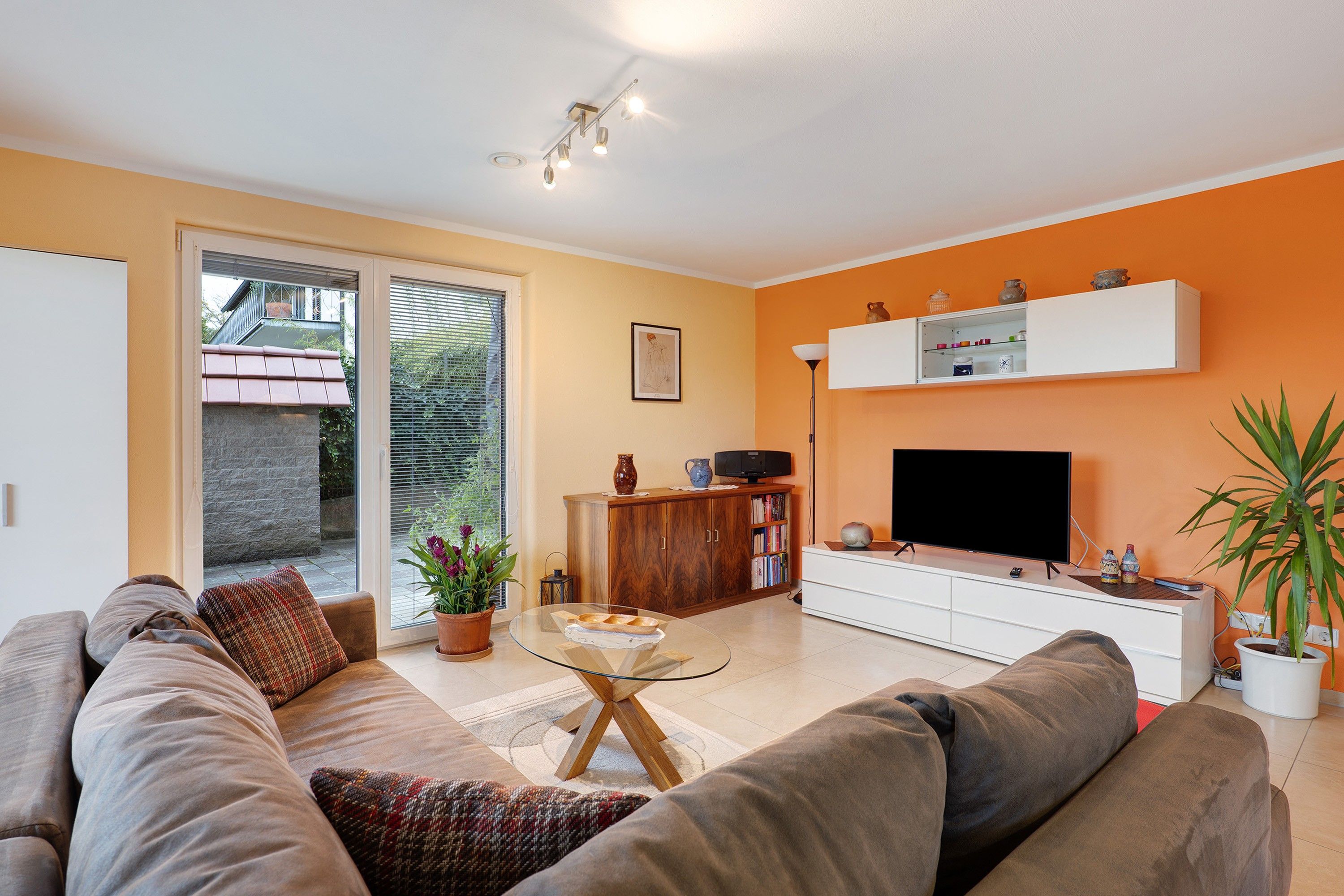 Una sala de estar con sofá, mesa de centro, televisor y mueble.