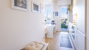 Un couloir étroit, avec une kitchenette sur la droite, un petit coin salon doté d’un coussin et un balcon offrant une vue agréable.