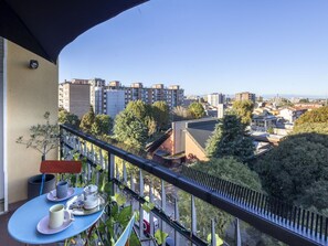A balcony with a table set for two, overlooking a cityscape with buildings and trees. - Beautiful apartment for 2 guests with WIFI, A/C, TV, balcony and pets allowed (Milan)