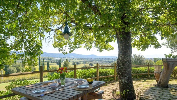 Une table de pique-nique en bois installée à l’extérieur, offrant une vue sur la campagne.