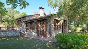Une maison en pierre avec une cheminée en pierre, des volets en bois et un mur en pierre.