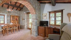 Un intérieur rustique avec un mur en pierre, des meubles en bois et un téléviseur.