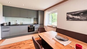 Eine moderne Küche mit grauen Schränken, einem Holztisch und einem schwarz-weißen Landschaftsbild an der Wand.