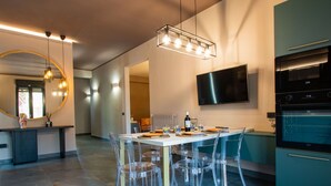 A modern kitchen with a dining area, featuring a large mirror, pendant lights, and a built-in oven.