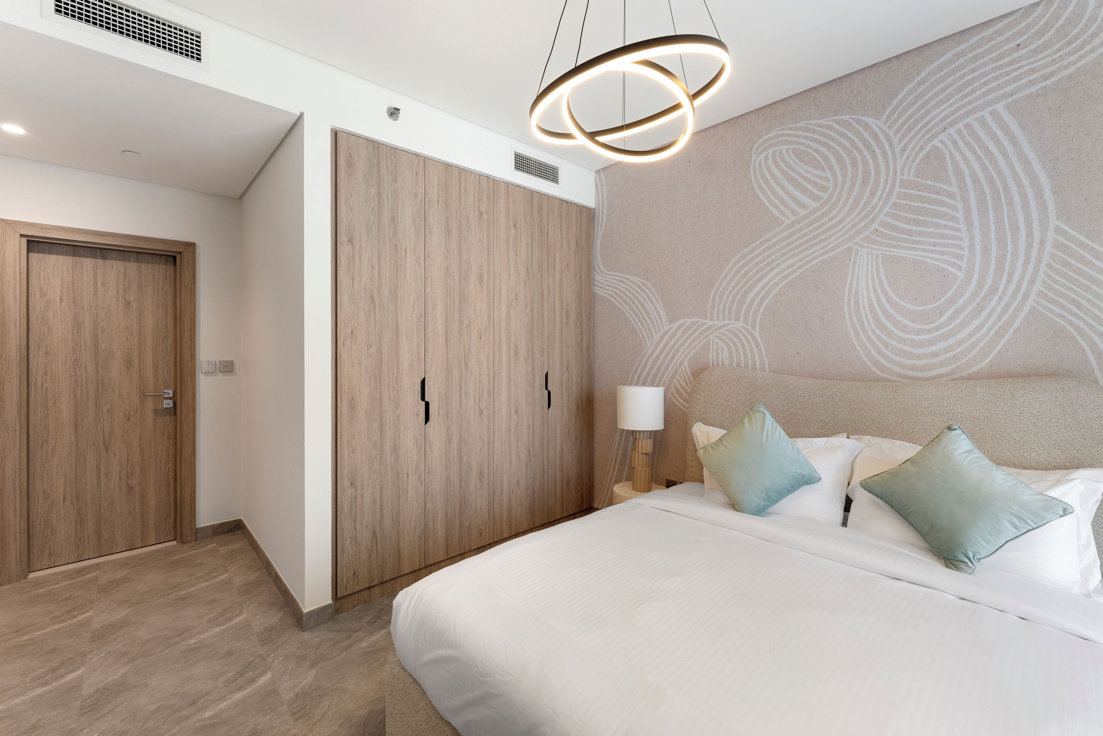 Een moderne slaapkamer met een groot bed, een houten garderobe en een bijzonder wandontwerp.