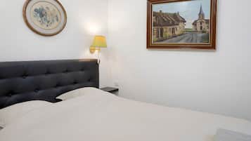 A hotel room with a bed, a framed painting, a lamp, and a wall-mounted picture frame.