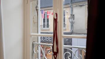 Une vue à travers une fenêtre ornée d’une rambarde en métal, avec un drapeau et une enseigne sur laquelle on peut lire « CIBE ».