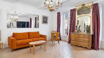Een kamer met een bank, een tafel, een kast en een kroonluchter.