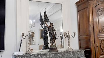 Una chimenea de mármol con una estatua, candelabros y un aparador de madera.