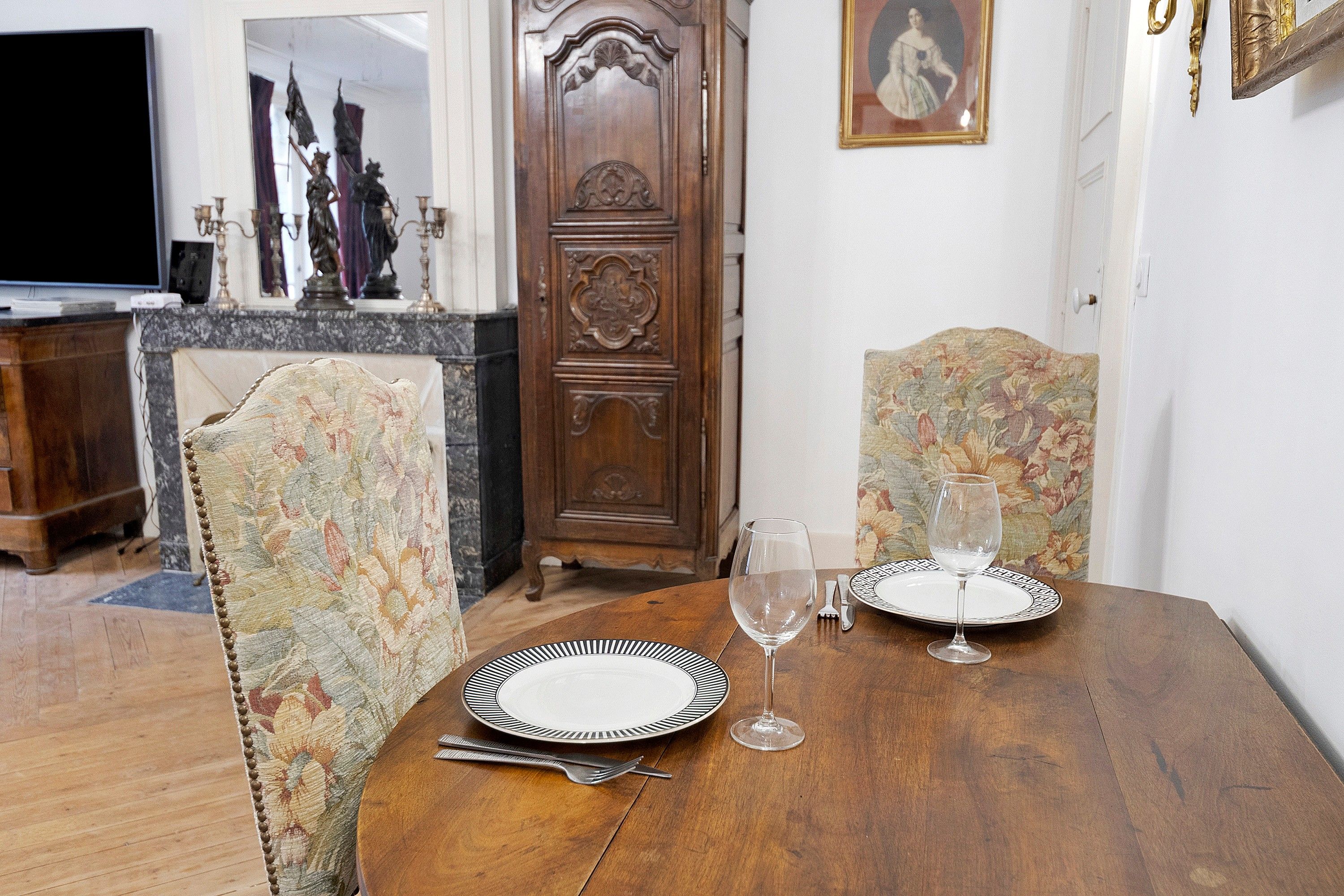 Een eettafel met twee stoelen, een wijnglas en bestek.