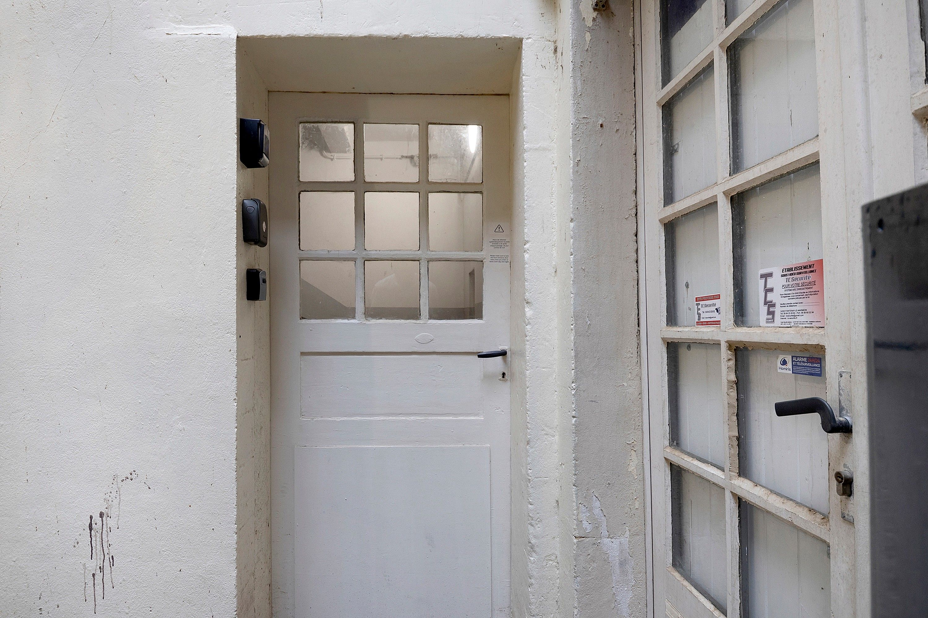 Uma porta branca com janela e olho-mágico, olho-mágico na porta e olho-mágico na janela.