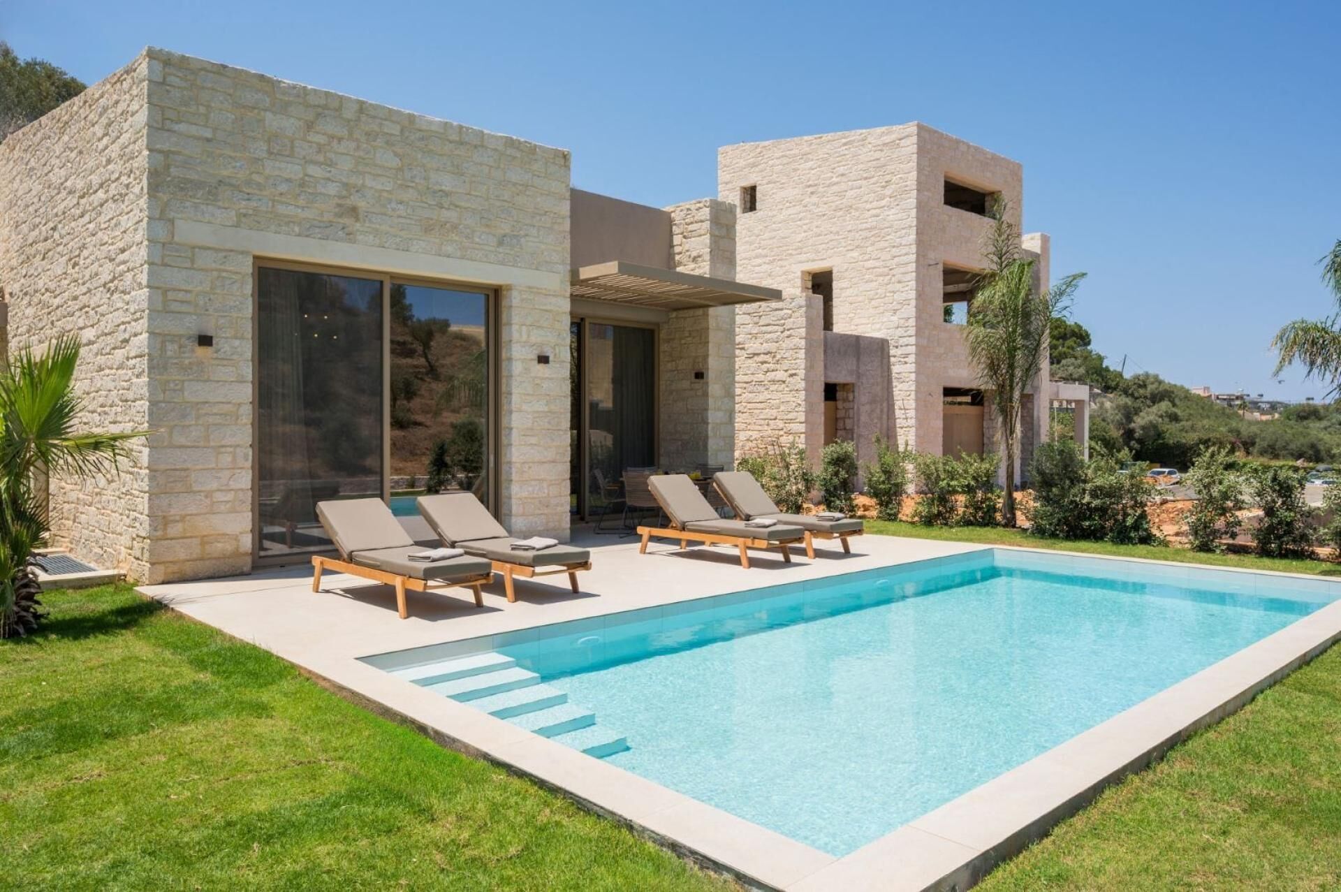 Eine moderne Villa mit Swimmingpool, Steinmauern und Sitzgelegenheiten im Freien.