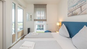 Quarto de hotel com uma cama grande, janela com persianas, vista para o exterior e um quadro na parede.