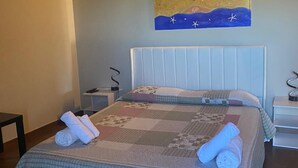 A neatly made bed with a quilt and rolled towels, a wall-mounted artwork, and a wooden ceiling. - Stone House Gebel el Son (Novi Velia)