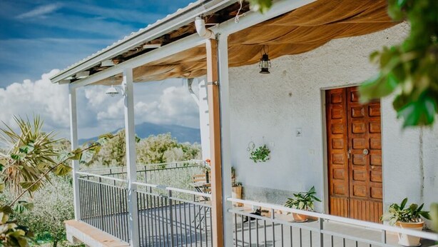 A balcony with a white railing, potted plants, and a wooden door. - Stone House Gebel el Son (Novi Velia)