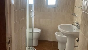 A bathroom with a glass shower enclosure, two toilets, and a sink. - Stone House Gebel el Son (Novi Velia)