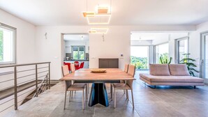 A modern dining area with a wooden table and chairs, a sofa, and a view of the kitchen and outdoors. - Stunning private villa for 8 guests with hot tub, WIFI, A/C, TV, terrace and panoramic view (Camerano)