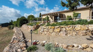 Una propietat de parets de pedra amb terrassa coberta i jardí.