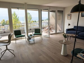 Un salon moderne avec un canapé, des fauteuils, une table basse et un balcon offrant une vue agréable.