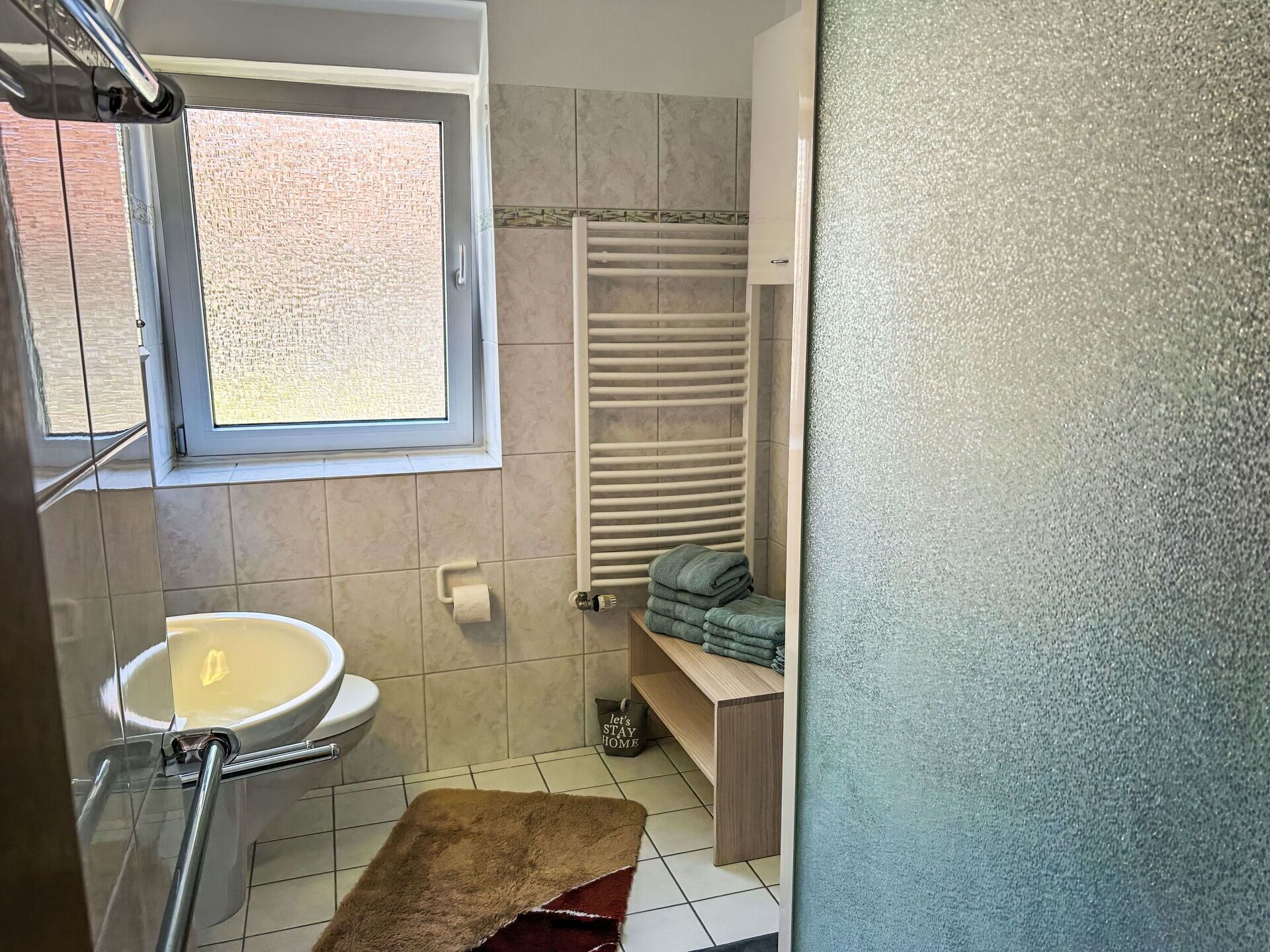 Et badeværelse med toilet, håndvask og et håndklædestativ.