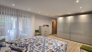 A modern bedroom with a large bed, a wardrobe, a desk, and a chair.