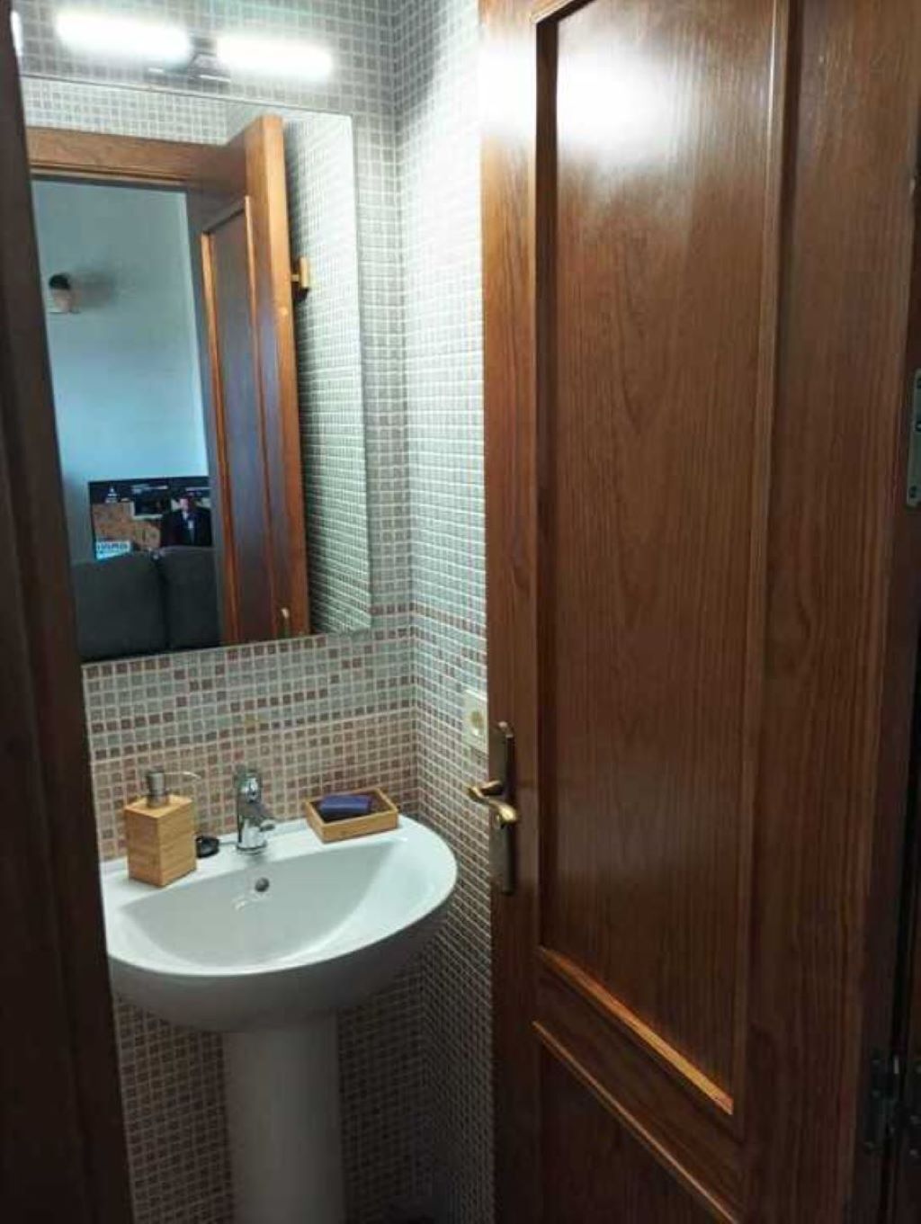 A bathroom with a white sink, a mirror, and a wooden door.