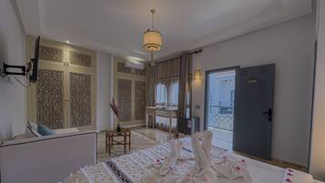 A hotel room with a bed, a seating area, a desk, and a view of the outside.