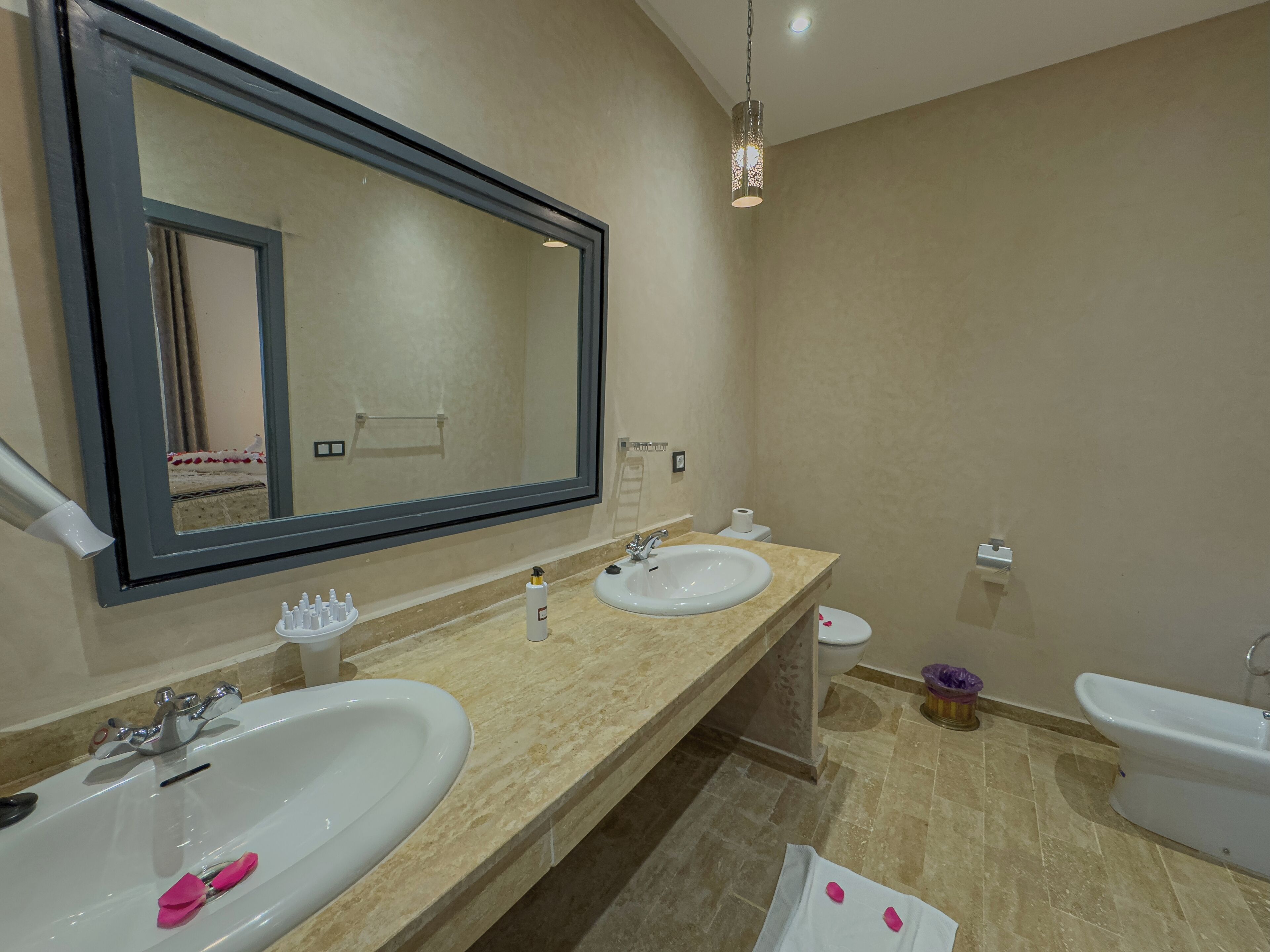 Une salle de bain moderne avec deux lavabos, un grand miroir, des toilettes et un bidet.
