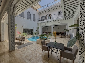 A spacious courtyard with a swimming pool, outdoor seating, and ornate architectural details.