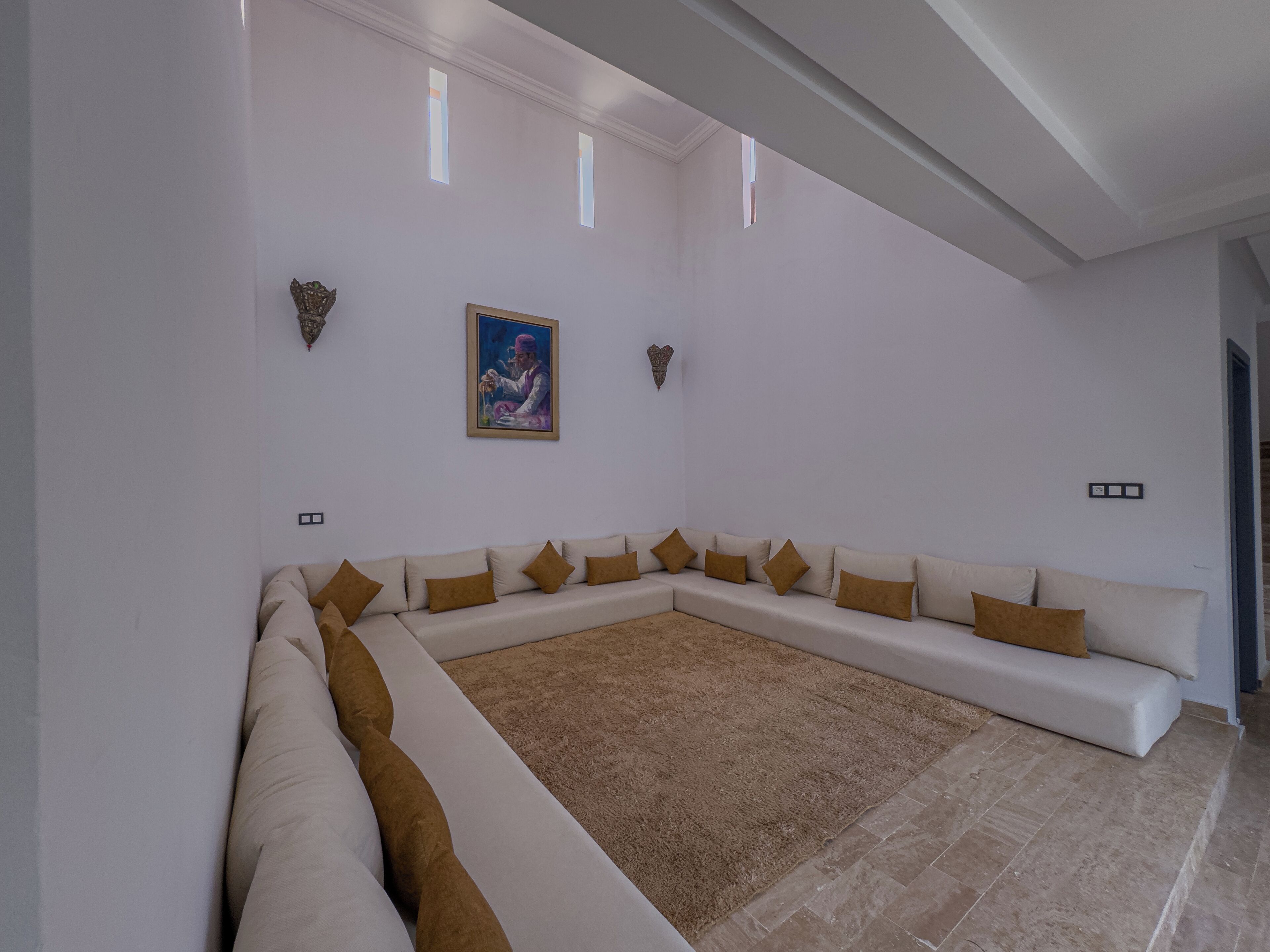 A spacious living room with a large L-shaped sectional sofa, a brown shag rug, and a painting on the wall.