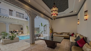 A luxurious living room with a pool, ornate ceiling, and comfortable seating. - Riad Tonaroz Gold (Marrakech)