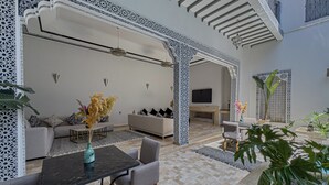 A spacious living area with a sofa set, a dining table, and a TV mounted on the wall. - Riad Tonaroz Gold (Marrakech)