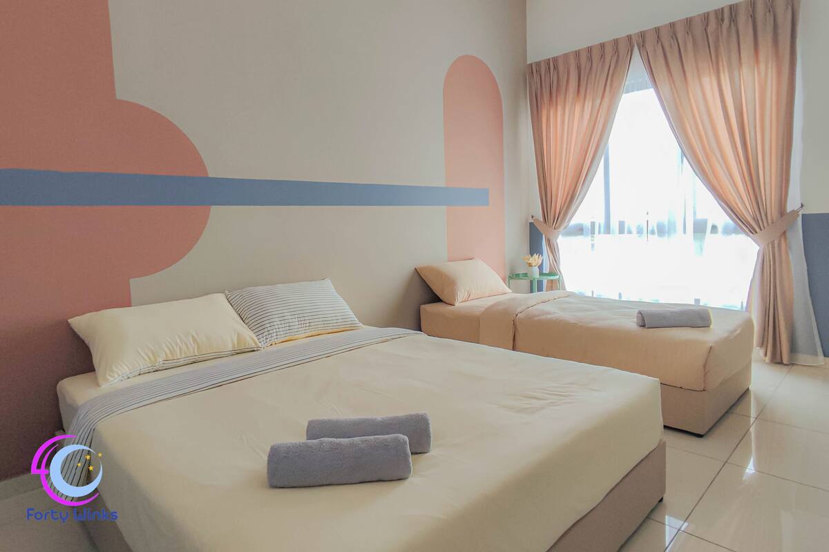 A hotel room with a large bed, a smaller bed, and a window with curtains.