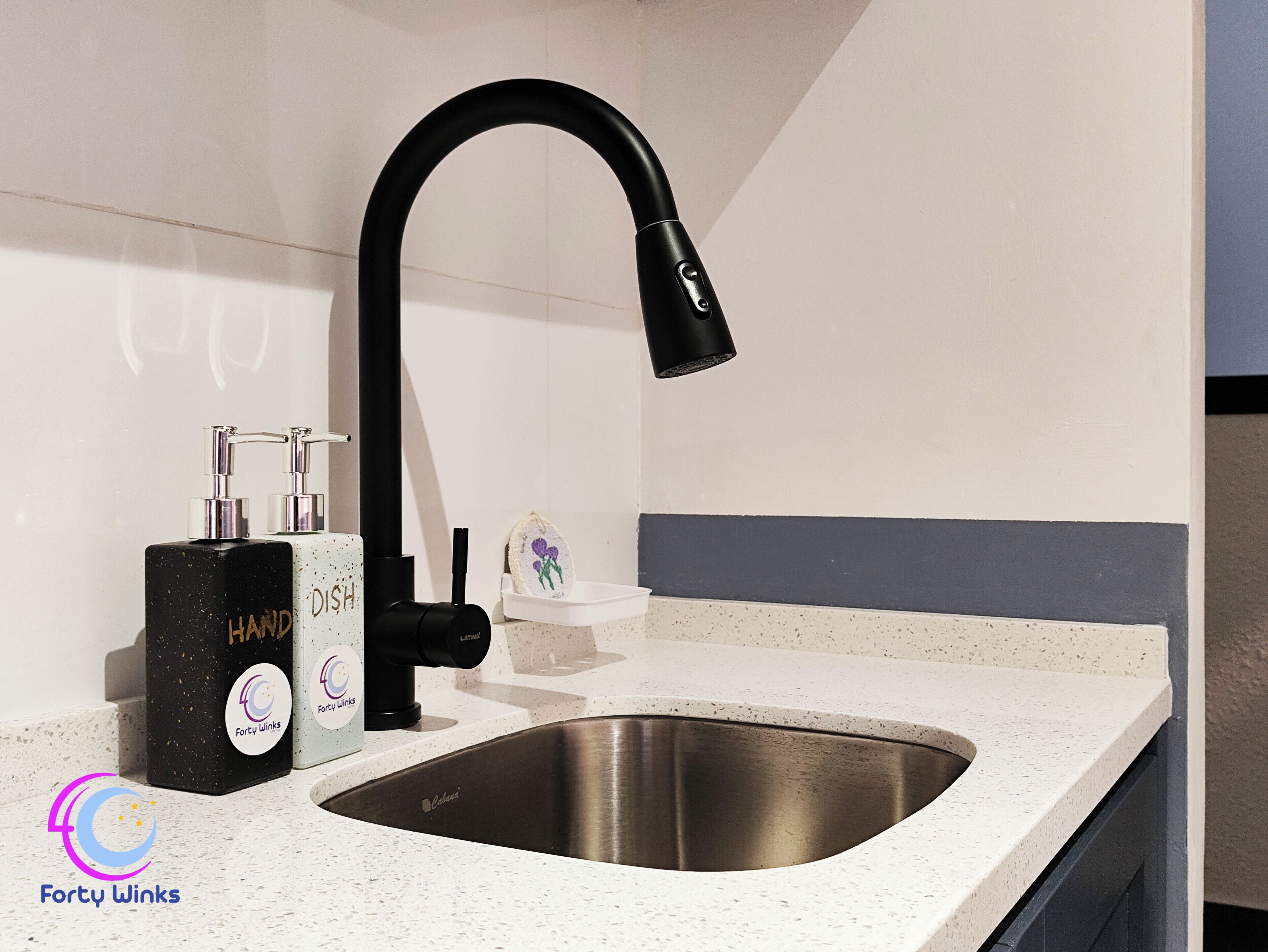 A modern kitchen with a stainless steel sink, a black faucet, and a soap dispenser.