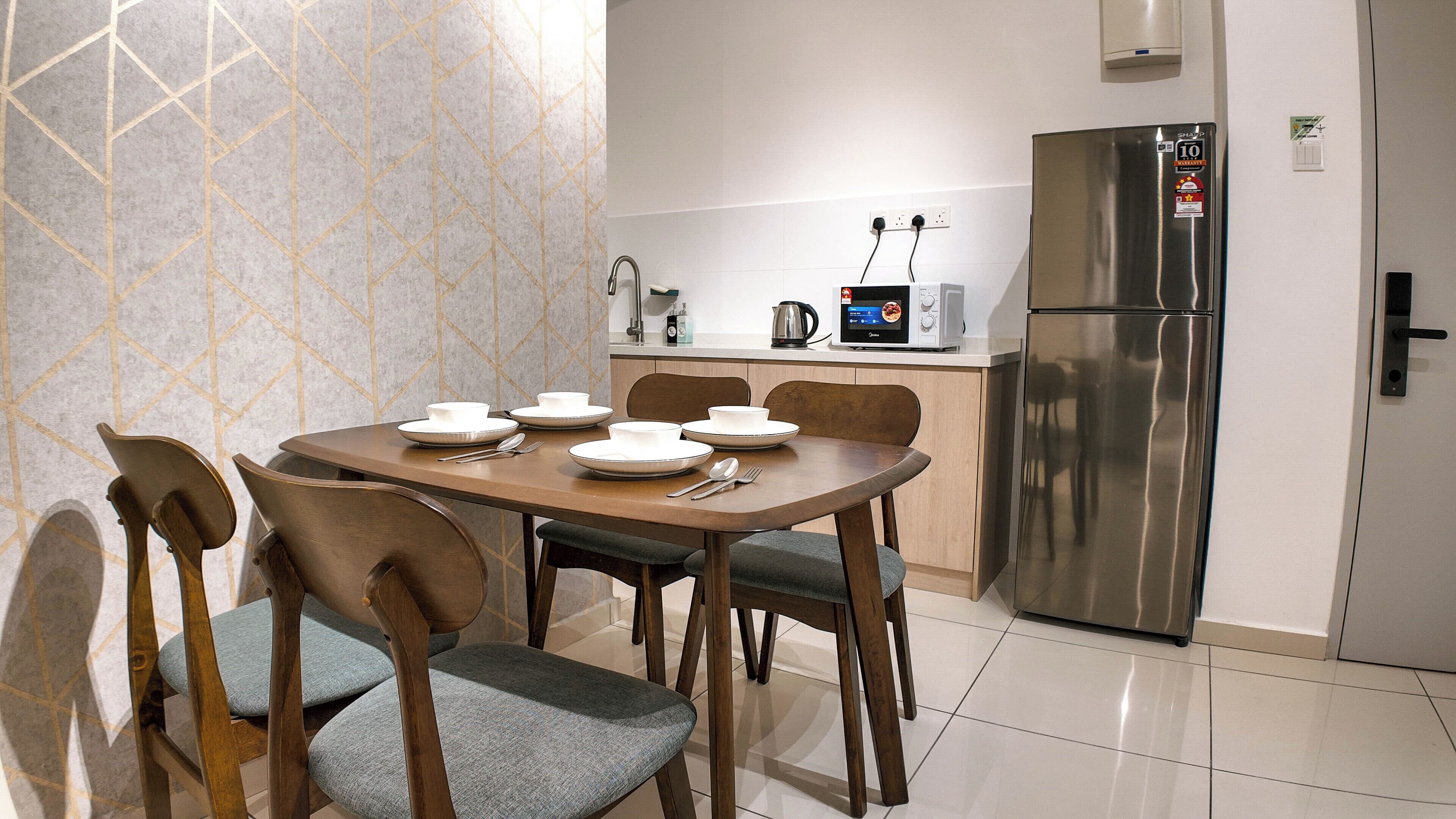A modern kitchen with a dining table set for four, a stainless steel refrigerator, and a microwave.