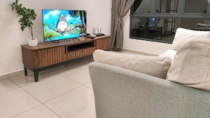 Un soggiorno con televisore a schermo piatto su un mobile in legno, una pianta in vaso e un divano.