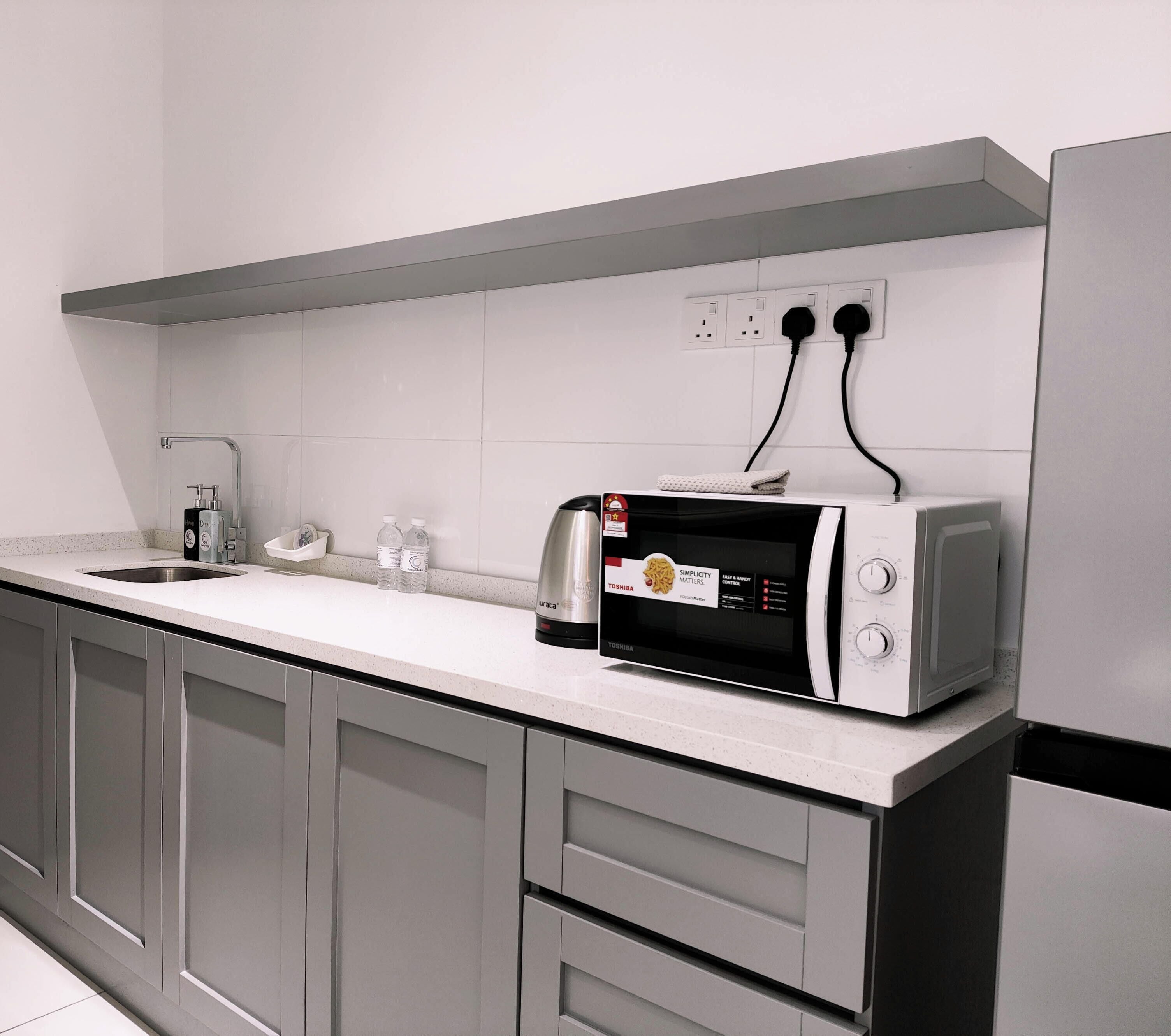 Una cocina equipada con microondas, lavamanos y armarios.