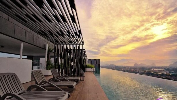 Area piscina sul tetto con poltrone relax e vista sulla città al tramonto.